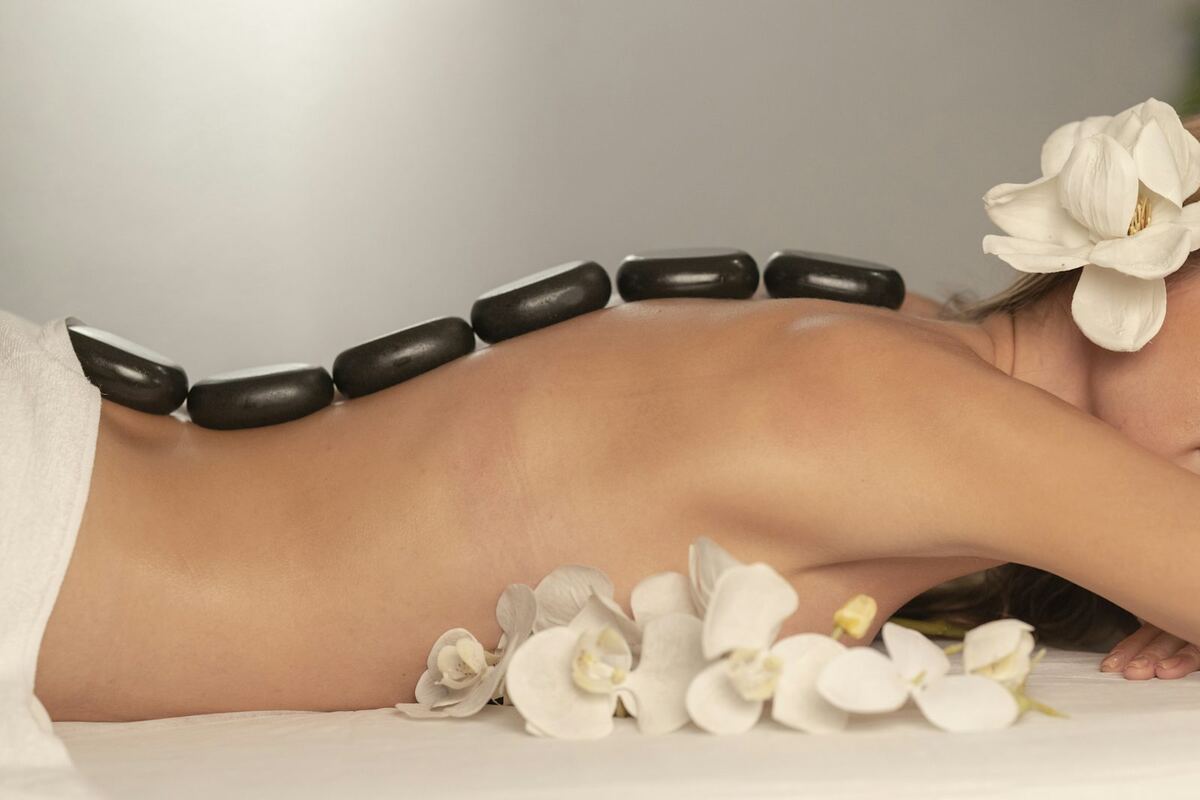 Persona recibiendo masaje con piedras calientes en spa